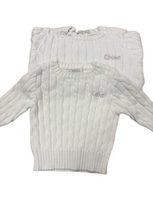 Two white cable-knit sweaters with embroidered names