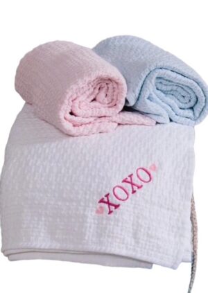 White towel embroidered XOXO with pastel rolls