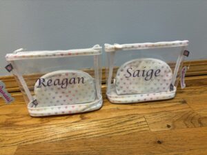 Two clear personalized pouches labeled Reagan and Saige