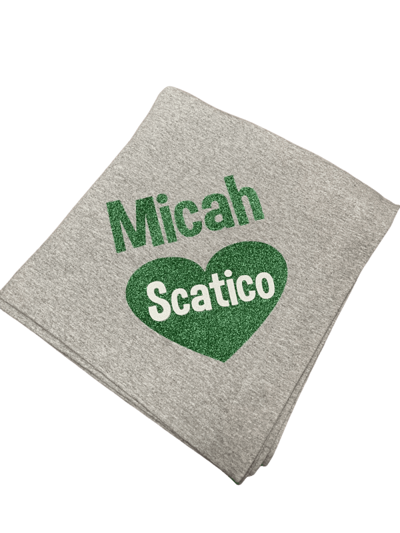 Folded gray shirt with green heart Micah Scatico
