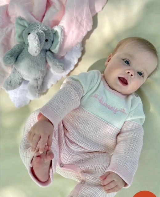 Smiling baby lying with stuffed elephant